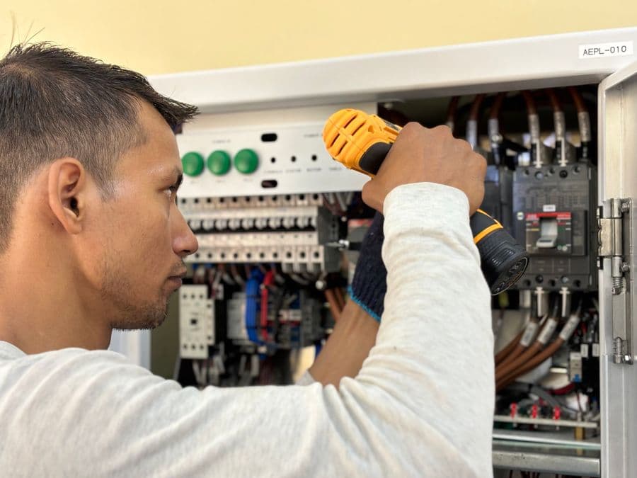 An electrician working on a home circuit-breaker panel — local home-service work