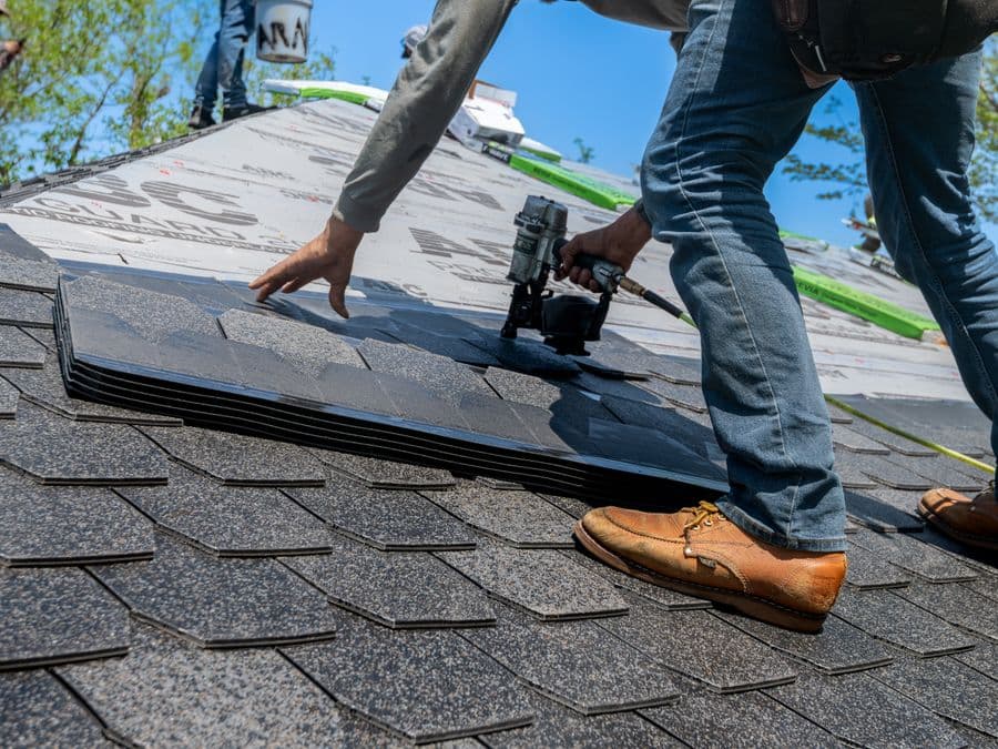A roofer installing shingles on a residential roof